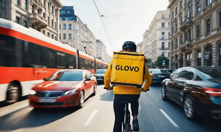 Glovo dostavljač vozi bicikl kroz gradsku gužvu